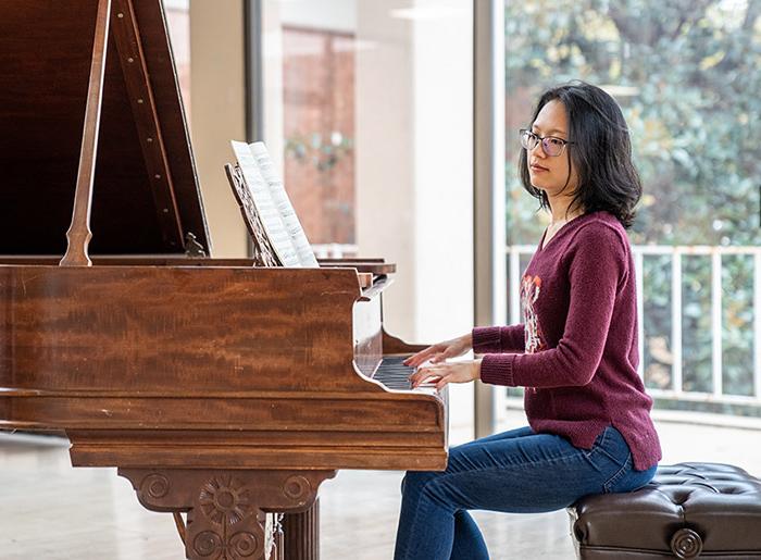 A Converse student plays a piece of music they composed at a piano.